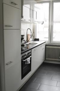 een witte keuken met een fornuis en een wastafel bij RuhrpottImmo - Zentrale Wohnung in Iserlohn - bis zu 7 Pers in Iserlohn