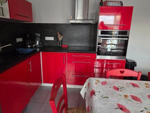 a red kitchen with red cabinets and a table at Chez sally in Le Bouchaud