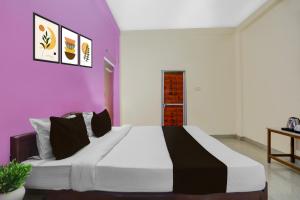 a bedroom with a large bed with purple walls at Hotel O BABA GUEST HOUSE in Shivāpur