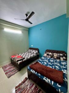 Dos camas en una habitación con paredes azules. en Rudraksh Homestay, en Ujjain
