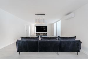 Una sala de estar con un sofá negro y un televisor. en Exclusive villa with ocean and mountain views in San Miguel, en San Miguel de Abona