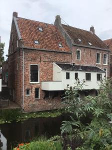 Una vieja casa de ladrillo con un río enfrente. en Solwerderstraat 12 - Hangende Keuken, en Appingedam