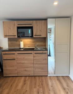 a kitchen with wooden cabinets and a sink at LippeStay - Modernes Apartment für 2 in Werne an der Lippe