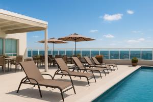 a row of chairs and umbrellas next to a swimming pool at Saint Moritz Hplus Express in Brasilia