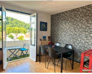 a dining room with a brick wall and a table and chairs at Le cocon in Jurançon