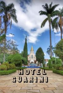 a sign in front of a building with palm trees at Hotel Guarini in Monte Sião