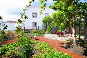a garden with a white house with tables and chairs at AngrA + in Angra do Heroísmo +41 photos