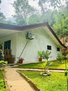 a small white house with a window and plants at Holiday Home Rathnaella in Hassalaka