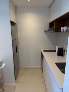 a white kitchen with a sink and a refrigerator at Segundo hogar in Luján +5 photos