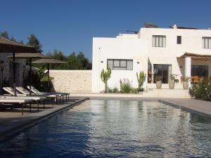 a pool in front of a house with chairs and a building at Les Agaves in Oulad el Madani