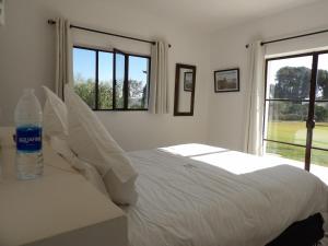 a white bedroom with a bed with a bottle of water on it at Les Agaves in Oulad el Madani +97 photos