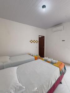 two beds in a white room with a window at Pousada Ventos Pécem in São Gonçalo do Amarante