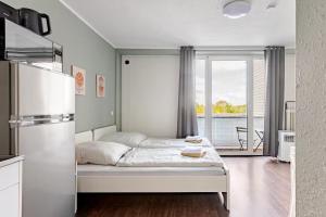 a white bedroom with a bed and a large window at Exklusiv Küche Office Streaming Minibar in Bonn