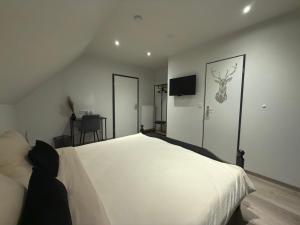 a bedroom with a large white bed and a flat screen tv at Landhaus Pension Jagdschlösschen in Willingen