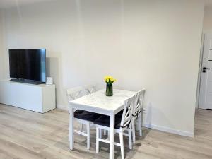 a white table with chairs and a vase of flowers on it at Modern 2023 apartment in Kutno