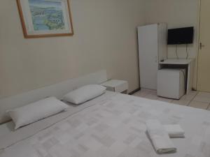 Un dormitorio blanco con una cama blanca y un televisor. en Hotel Solemio, en Aracaju