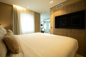 a bedroom with a white bed and a flat screen tv at Radisson Vila Olimpia Sao Paulo in São Paulo
