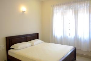 a bedroom with a bed and a window with white curtains at First House Mihintale in Mihintale