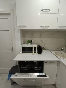 a white kitchen with a microwave on a counter at The Friendly Apartment in Turda