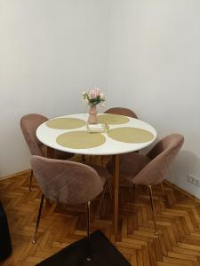 a table with chairs and a vase with flowers on it at The Friendly Apartment in Turda