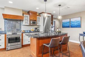a kitchen with a large island with bar stools at Cozy 2BR Retreat Mountain View with Pool and Hot Tub in Canmore