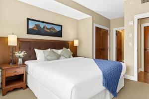 ein Schlafzimmer mit einem großen weißen Bett und einem Nachttisch in der Unterkunft Spacious Rockies Escape near Banff Hot tub and Gym in Canmore