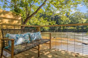 a bench on a deck with a view of a field at Breezy - Riverfront Tiny Home, King Bed, and Deck! in Sylva