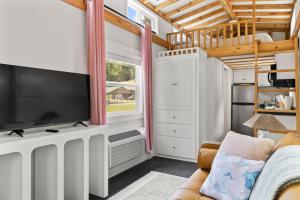 a living room with a tv and a couch at River Run - Riverfront Tiny Home, Trails, and Views! in Sylva