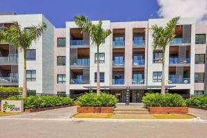 an apartment building with palm trees in front of it at Elegant 3BR Condo Near Airport in Punta Cana