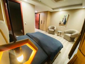 una habitación de hotel con una cama y sillas. en Gold Crest Apartments Luxurious, en Lahore 99 fotos más