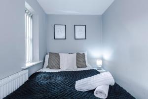 une chambre blanche avec un lit avec des serviettes dessus dans l'établissement Spacious 3-BR Escape in Coseley with Free Parking, à Coseley 4 autres photos