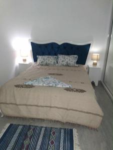 a bedroom with a large bed with blue pillows at Dar Leïla in Harqalah