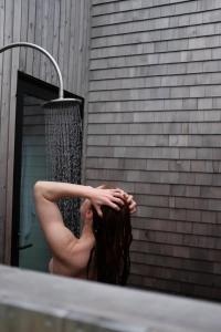 Una donna in piedi davanti alla doccia di Cedar - Luxury 2 Bdrm Cottage a Chimney Corner