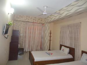 1 dormitorio con 2 camas y ventilador de techo en Muscat Holiday Resort, en Cox's Bazar