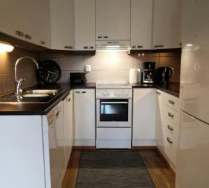 cocina con armarios blancos, fregadero y horno en Modern Apartment for 2 with Sauna, en Kemi