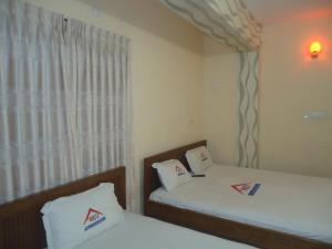 two beds in a room with a window at Muscat Holiday Resort in Cox's Bazar