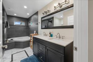 a bathroom with a tub and a sink and a bath tub at The Modern Re-Joyce Retreat in Hamilton Acres +36 photos