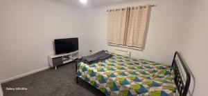 a bedroom with a bed and a flat screen tv at Milton Court in Goodmayes