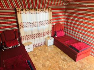 a room with a red couch and a striped wall at Dana Sunset camp in Nijil