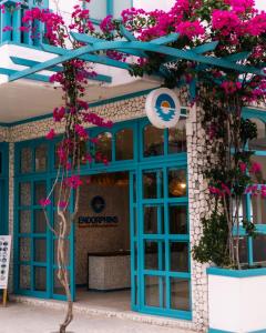 a building with blue doors and pink flowers at Endorphins Beach Villa in Dhiffushi