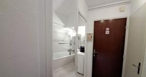 a white kitchen with a brown door in a room at Coup de cœur 3 étoiles terrasse parking Wifi à 70 m des thermes in Amélie-les-Bains-Palalda