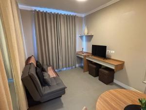 a living room with a couch and a desk with a computer at Ravello Residencial, Perto do Centro e da Ponte da Amizade in Foz do Iguaçu