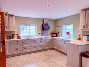 a large kitchen with white cabinets and a window at Tollbar Cottage in Penrith