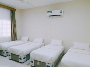 three beds in a room with a air conditioner at هومي 2 in Salalah