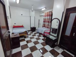 a room with a bed and a mirror and a checkered floor at Mayane guesthouse in Luxor +2 photos
