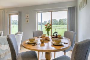 ein Esszimmer mit einem Holztisch und Stühlen in der Unterkunft Beech View 1 in Corsley