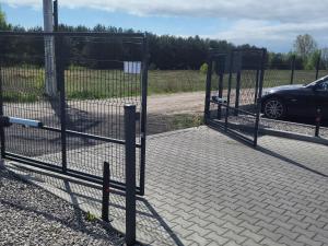 a gate to a parking lot with a car at Modern 2023 apartment in Kutno