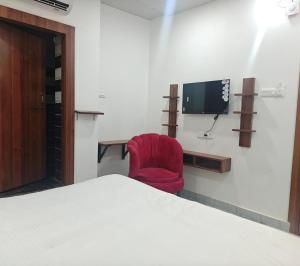 a room with a bed and a red chair and a tv at Hotel Royal Krishna in Gorakhpur +5 photos