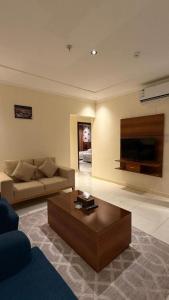 a living room with a couch and a coffee table at نصف القمر للشقق المخدومة in Ḩaql