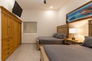 a bedroom with two beds and a flat screen tv at Beachfront luxury Condo w Pool in Cabo San Lucas